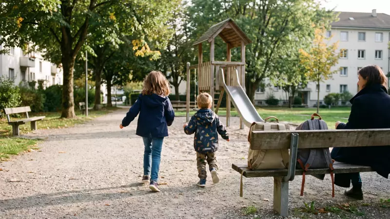 Deux enfants posent leurs sacs d’école sur un banc et courent vers une place de jeux en fin d’après-midi