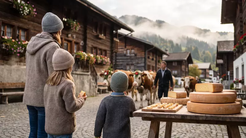 Une mère et ses deux enfants, vus de dos, goûtent du fromage d’alpage à un stand pendant une désalpe dans un village de montagne