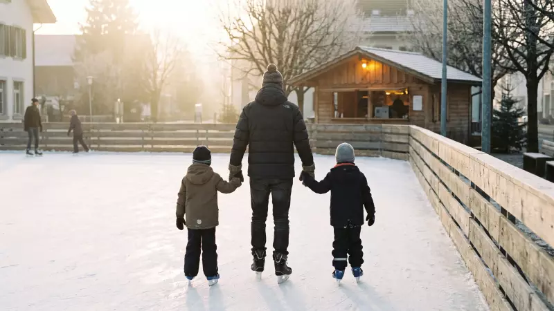 Un parent et deux enfants patinent main dans la main, de dos, sur une patinoire de plein air en fin d'après-midi, illustration IA