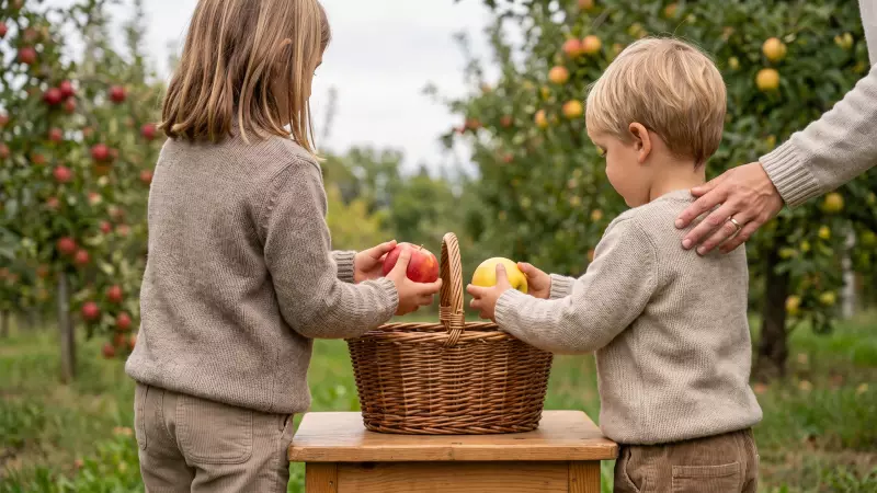 Deux enfants, vus de dos, s’apprêtent à déposer une pomme dans un petit panier au verger, la main d’un adulte posée sur l’épaule du plus jeune