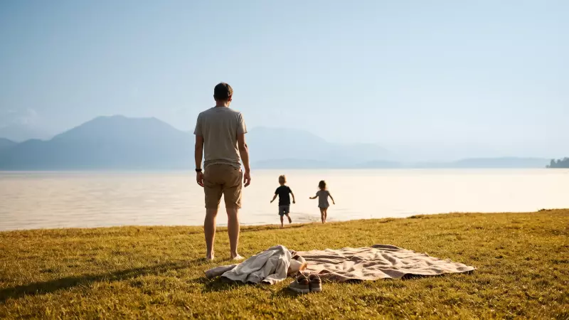 Deux enfants courent vers l’eau peu profonde d’un lac suisse en fin d’après-midi de septembre, un parent les observe depuis la rive